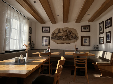Dürscheider Hof - Innenansicht Gemütliches Restaurant mit Holztischen, stimmungsvollem Licht und rustikaler Wanddekoration.