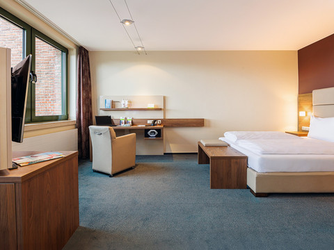 Doppelzimmer Ein modernes Hotelzimmer mit gemütlichem Einzelbett, Schreibtisch, Fernseher und großem Fenster.