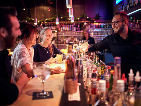 Bar Fröhliche Menschen unterhalten sich in einer gemütlichen Bar, während der Barkeeper Cocktails serviert.