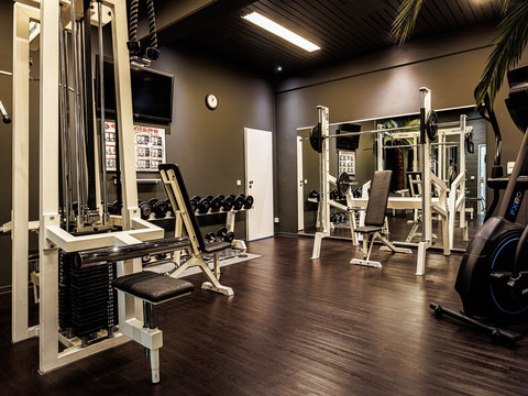 Fitnessraum Ein modernes Fitnessstudio mit Gewichten, Kraftgeräten und großen Spiegeln in einem stilvollen Ambiente.