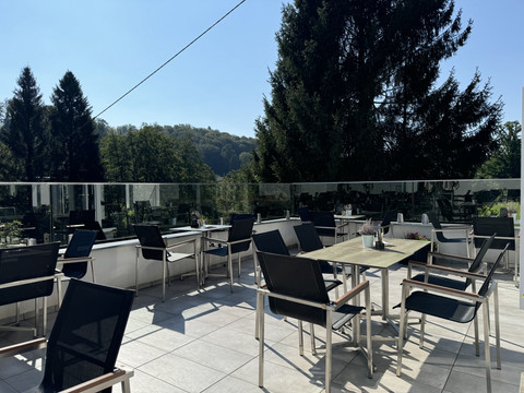 Kaffeerösterei Pagnia - Ansicht Außenterrasse Große Terrasse eines Cafés oder Restaurants mit modernen Sitzgelegenheiten und Blick auf Waldlandschaft.