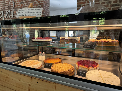 Kaffeerösterei Pagnia - Ansicht Kuchentheke Vielfältige Auswahl an leckeren Kuchen und Torten in einer Glasvitrine einer Bäckerei.