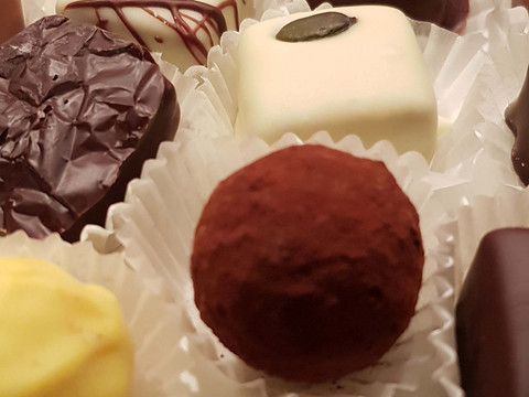 Pralinenadvent.jpg Eine Auswahl an handgemachten Pralinen in verschiedenen Formen und Farben auf einem Tablett.