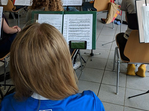 Jugendherberge Lindlar Orchesterprobe: Junge Musiker in einem hellen Raum, fokussiert auf Notenständer mit Partituren.