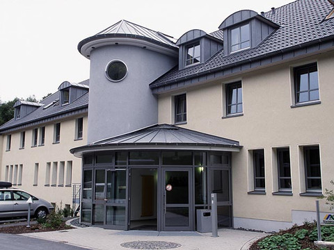 Jugendherberge Wiehl Ein modernes, zweistöckiges Gebäude mit Rundturm und großen Fenstern, daneben ein geparktes Auto.