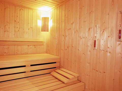 Jugendherberge Wiehl Helle Holzsauna mit Bänken, warmes Licht und zwei Thermometern an den Holzwänden. Entspannende Atmosphäre.
