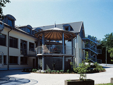 Jugendherberge Wiehl Modernes, zweistöckiges Gebäude mit rundem, überdachtem Balkon und umliegender Grünfläche.