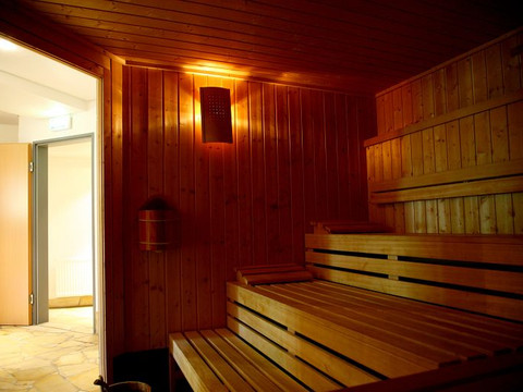 Jugendherberge Wiehl Holzverkleidete Sauna mit sanfter Beleuchtung, Bänken und offener Tür; einladende, gemütliche Atmosphäre.