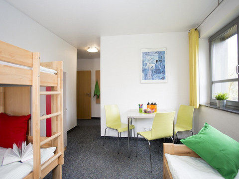 Jugendherberge Wiehl Ein freundliches, helles Zimmer mit Stockbett, Tisch, Stühlen und einem Fenster mit Tageslicht.