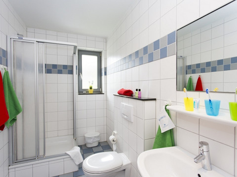 Jugendherberge Wiehl Helles Badezimmer mit Dusche, WC, Waschbecken und bunten Handtüchern in einem neutralen Design.