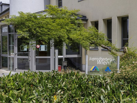 Jugendherberge Wiehl Eingang der Jugendherberge Wiehl mit grünen Pflanzen und einem Schild, das den Namen zeigt.