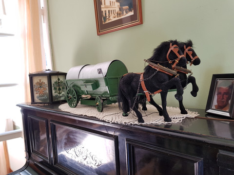 Pulvermuseum Ohl <p>Miniaturgespann mit schwarzem Pferd und grünem Wagen auf antikem Klavier.</p>