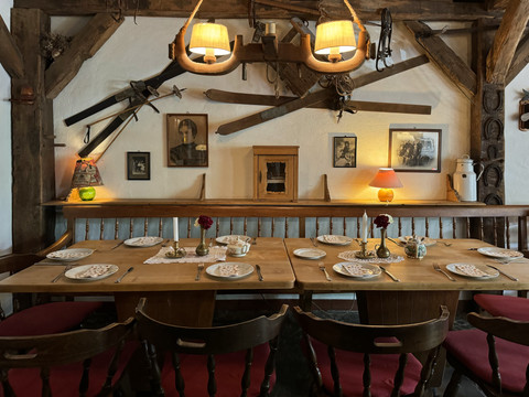Pfannkuchenhaus Nümbrecht - Innenansicht gedeckter Tisch Rustikales Wirtshausinterieur mit Holztischen, antiken Skiern an der Wand, und stilvoll gedecktem Tisch.