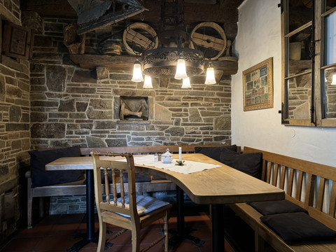 Pfannkuchenhaus Nümbrecht - Innenansicht Gemütliche, rustikale Gaststube mit Holztischen, einer Bank und einem antiken Kronleuchter.