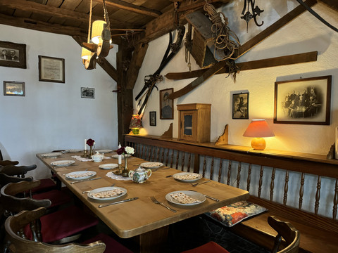 Pfannkuchenhaus Nümbrecht - Innenansicht gedeckter Tisch Gemütliche Stube mit rustikalem Holztisch, dekoriert mit historischen Gerätschaften und Schwarz-Weiß-Fotos.