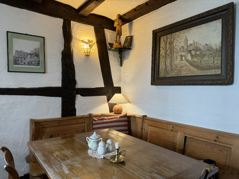 Pfannkuchenhaus Nümbrecht - Innenansicht Sitzecke Gemütlicher rustikaler Gastraum mit Holzbänken, antiken Bildern und stimmungsvoller Beleuchtung.