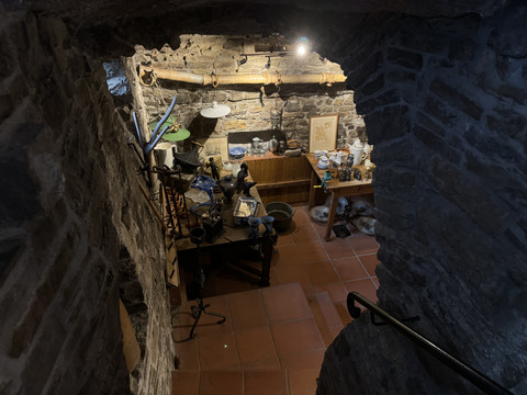 Pfannkuchenhaus Nümbrecht - Ansicht Verkaufsraum Ein historischer Kellerraum mit Steinwänden, alten Möbeln und antiken Haushaltsgegenständen.