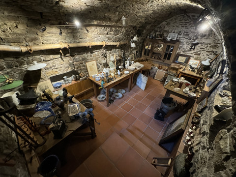 Pfannkuchenhaus Nümbrecht - Ansicht Verkaufsraum Rustikaler Gewölbekeller mit Antiquitäten und Haushaltsgegenständen auf dem Boden und Regalen.