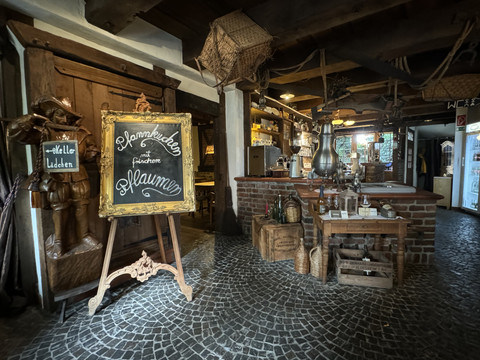 Pfannkuchenhaus Nümbrecht - Innenansicht Gemütliche, rustikale Café-Einrichtung mit Holzmöbeln und Kreidetafel, die Pflaumenkuchen anbietet.