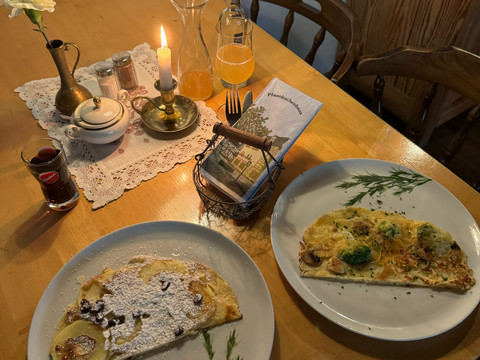 Pfannkuchenhaus Nümbrecht - Ansicht Pfannkuchen Ein gemütlich gedeckter Tisch mit zwei Tellern Pfannkuchen, Kerze, Getränken und Besteck.