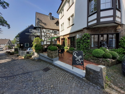 Pfannkuchenhaus Nümbrecht - Außenansicht Fachwerkhäuser mit Garten und Café in malerischer Kopfsteinpflastergasse in Nümbrecht.
