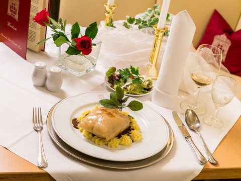 Zelná roláda v restauraci hotelu Romantik Deutsches Haus Pirna Elegant gedeckter Tisch mit einem Teller gefülltem Kohl auf Kartoffelpüree, Salat, Rotweinglas, Kerzen und einer roten Rose in einer Vase.Elegantly laid table with a plate of stuffed cabbage on mashed potatoes, salad, red wine glass, candles and a red rose in a vase.Elegantně prostřený stůl s talířem plněného zelí na bramborové kaši, salátem, sklenkou červeného vína, svíčkami a červenou růží ve váze.Elegancko nakryty stół z talerzem gołąbków na puree ziemniaczanym, sałatką, kieliszkiem czerwonego wina, świecami i czerwoną różą w wazonie.Elegant gedekte tafel met een bord gevulde kool op aardappelpuree, salade, rode wijn, kaarsen en een rode roos in een vaas.Tavola elegantemente apparecchiata con un piatto di cavolo ripieno su purè di patate, insalata, bicchiere di vino rosso, candele e una rosa rossa in un vaso.