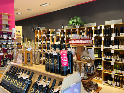 Barrique In einem Geschäft sind hohe Regale an den Wänden, die mit vielen verschiedenen Weinflaschen gefüllt sind.