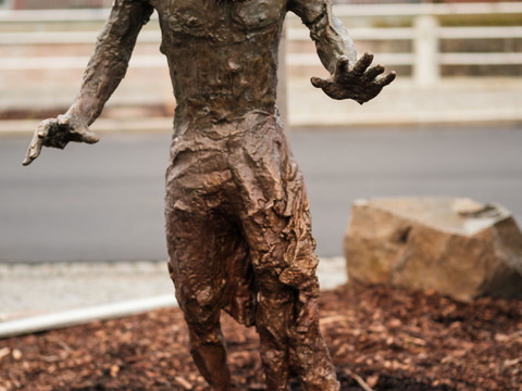 03_KSC_Collateral Sculptures_Thomas_Cyberfaun.jpg Skulptur eines menschenähnlichen Wesens mit Astgeweih, ausgestreckten Armen, stehend auf Mulch.Sculpture of a human-like creature with branch antlers, outstretched arms, standing on mulch.Socha člověku podobného tvora s parožím z větví, s roztaženýma rukama, stojícího na mulči.Rzeźba człekopodobnej istoty z porożem i wyciągniętymi ramionami, stojącej na ściółce.Sculptuur van een mensachtig wezen met een gewei van takken, uitgestrekte armen, staand op mulch.Scultura di una creatura umana con corna di ramo, braccia tese, in piedi su pacciame.