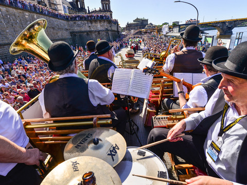 Dixielandfestival-Dixieland-Parade-2-©-Foto-Hendrik-Meyer.jpg Musicians in traditional costumes play jazz at a cheerful parade next to a river.