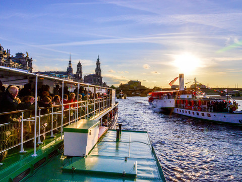 Dixielandfestival-Riverboat-Shuffle-1-©-Foto-Hendrik-Meyer.jpg Two historic steamboats sail at sunset on a river full of people.