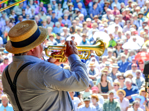 Dixielandfestival-Open-Air-Gala-1-©-Foto-Hendrik-Meyer.jpg A musician plays the trumpet in front of a large, summery open-air audience.