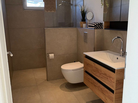 Bad_01 Modernes, barrierefreies Badezimmer mit begehbarer Dusche, hängendem WC und Waschtisch aus Holz.