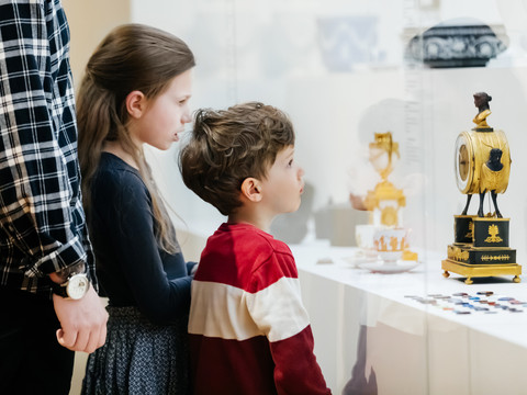 Zwei Kinder betrachten eine historische Uhr in der Ausstellung des GRASSI Museums für Angewandte Kunst am Johannisplatz in Leipzig