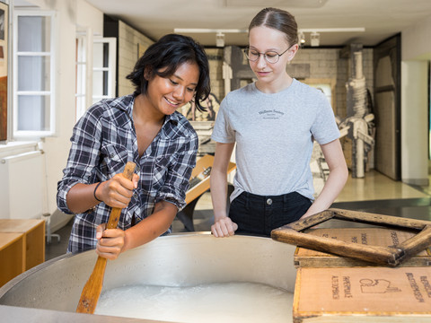 Papierschöpfen Zwei Frauen bei einer Vorführung des traditionellen Papierhandwerks in einem Museum.