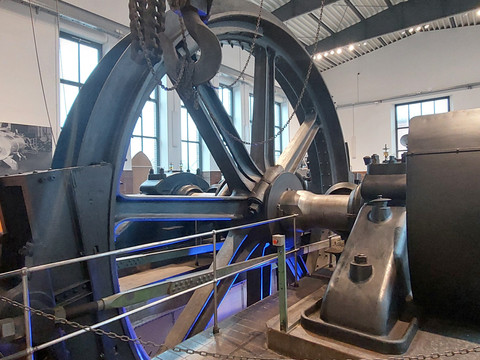 Industriedenkmal mit großer Schwungrad-Dampfmaschine in einem lichtdurchfluteten Raum.Industrial monument with large flywheel steam engine in a light-flooded room.Průmyslová památka s velkým setrvačníkovým parním strojem ve světlem zalité místnosti.Zabytek przemysłowy z dużą maszyną parową z kołem zamachowym w zalanym światłem pomieszczeniu.Industrieel monument met grote vliegwielstoommachine in een met licht overgoten ruimte.Monumento industriale con grande macchina a vapore a volano in una stanza illuminata.