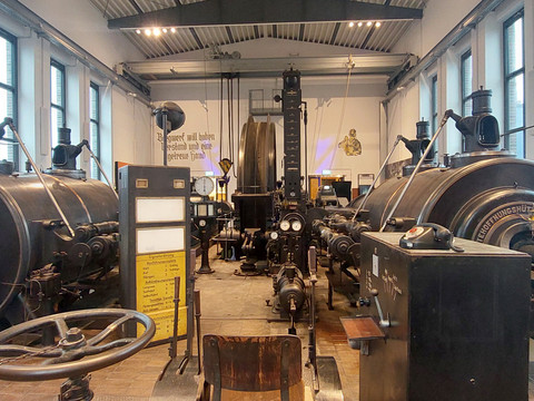 Historische Dampfmaschine in einem hellen Raum mit großen Fenstern und technischen Details.Historic steam engine in a bright room with large windows and technical details.Historický parní stroj ve světlé místnosti s velkými okny a technickými detaily.Zabytkowy parowóz w jasnym pomieszczeniu z dużymi oknami i szczegółami technicznymi.Historische stoommachine in een lichte kamer met grote ramen en technische details.Storica locomotiva a vapore in una luminosa sala con ampie finestre e dettagli tecnici.