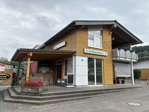 Gaststätte am Campingplatz Wiehltal <p>Zweistöckiges Holzgebäude mit Biergarten, Firmenschild "Im Himmelchen", umgeben von Natur.</p>