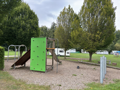 Spielplatz am Campingplatz Wiehltal <p>Ein Spielplatz mit Kletterwand, Rutsche und umliegenden Bäumen, auf einem Campingplatz in Wiehl.</p>