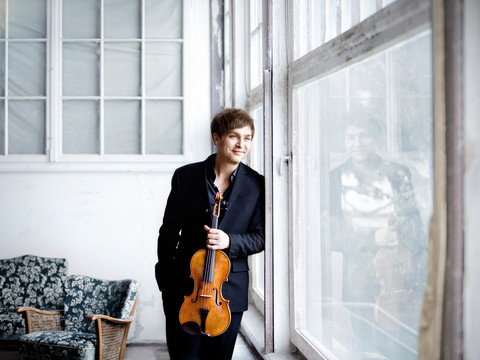 Nils Mönkemeyer_Press©Irène Zandel.jpg Nils Mönkemeyer lehnt lächelnd mit einer Viola an einem großen Fensterglas, spiegelt sich darin.