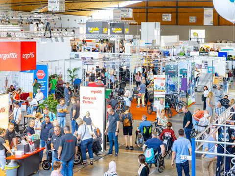rehab_2023_messekarlsruhe_juergenroesner_284.jpg Voller Betrieb auf einer Messe mit vielen Ständen und Besuchergruppen.