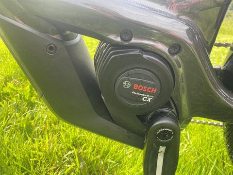 250 W Bosch middenmotor met 85 Nm koppel.jpg Close-up van een zwarte Bosch Performance Line CX e-bike motor op groen gras.