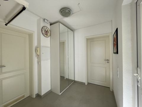 Flur Fewo grün Heller Flur mit drei Türen, großem Spiegel, Telefon an der Wand und runder Uhr über der Tür.
