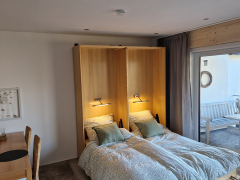 Schlafgelegenheit im Wohnzimmer Gemütliches Schlafzimmer mit zwei Einzelbetten, gedämpfter Beleuchtung und Zugang zu einem Balkon.