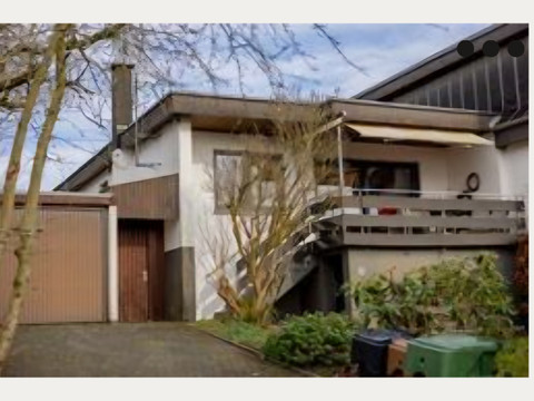 Ferienhaus "Boomen" Ein modernes Einfamilienhaus mit Garage und Balkon vor einer eingefriedeten Gartenanlage.