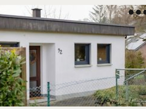 Ferienhaus "Boomen" Ein einstöckiges weißes Haus mit Flachdach und brauner Eingangstür, umgeben von grünem Garten.