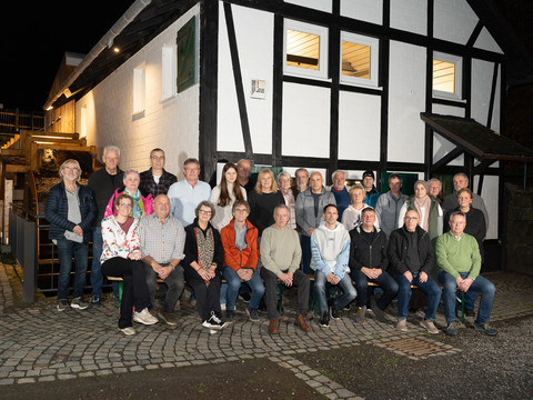 Dümmlinghauser Mühle Eine Gruppe von 32 Personen posiert vor einem weiß-schwarzen Fachwerkhaus auf gepflastertem Boden.