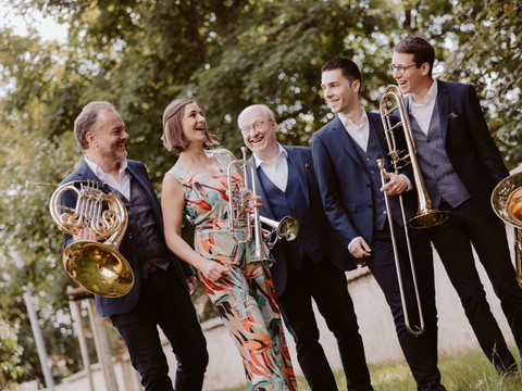 Harmonic Brass_Tobias Epp Fotografie.jpg Fünf Musiker in festlicher Kleidung mit Blasinstrumenten, im Freien lachend.