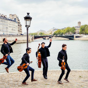 Quatuor Van Kujik 1 (c) Sylvain Gripoix.jpg Vier Musiker des Quatuor Van Kuijk springen dynamisch auf einer Pariser Uferpromenade, Violen in Händen, gekleidet in stilvollen schwarzen Anzügen vor einer charakteristischen Stadtlandschaft.