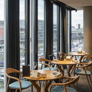 ox&klee Blick in ein stilvolles Restaurant mit großen Fensterfronten. Im Hintergrund Hafen und Domspitzen.View into a stylish restaurant with large window fronts. Harbor and cathedral spires in the background.