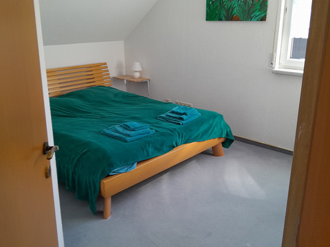 Ferienwohnung Preyersmühle Gemütliches Schlafzimmer mit großem Doppelbett, farbenfrohem Wandbild und Tageslicht durch das Fenster.